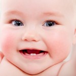 Close up of baby smiling with two bottom teeth